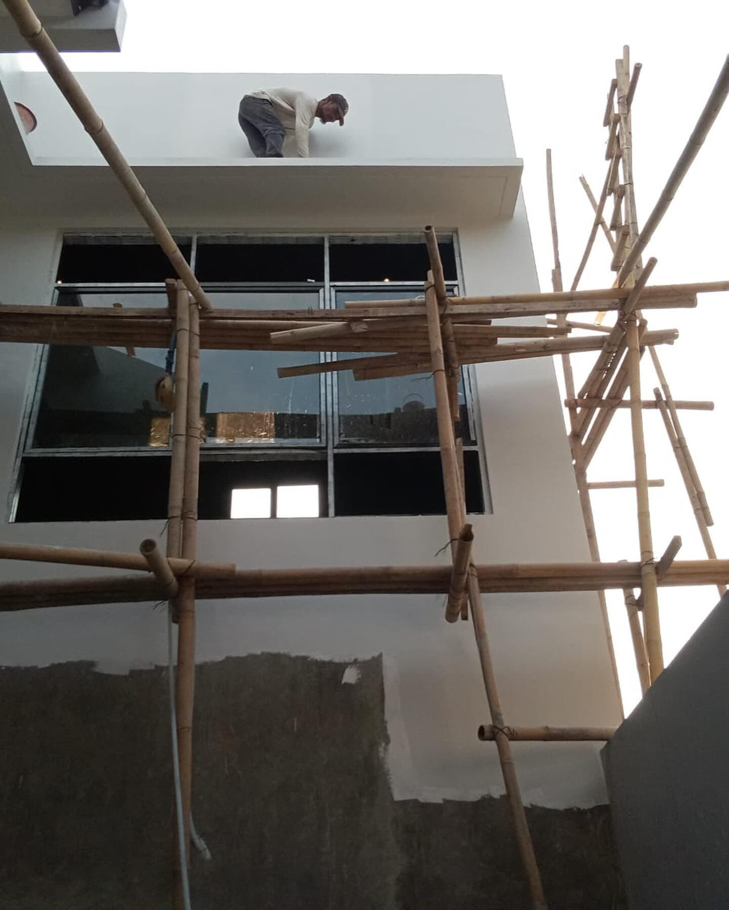Worker finishing the upper facade on bamboo scaffolding