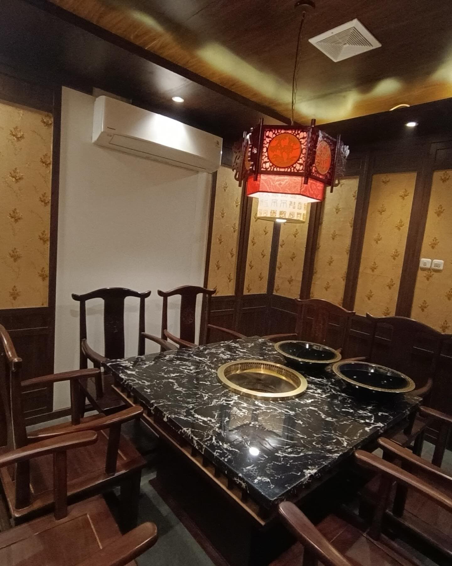 Dining room with a marble table, wooden chairs, and lantern lighting