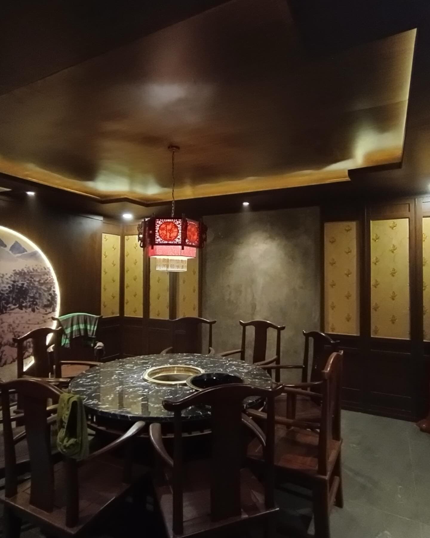 Round dining table under a circular mural with lantern lighting