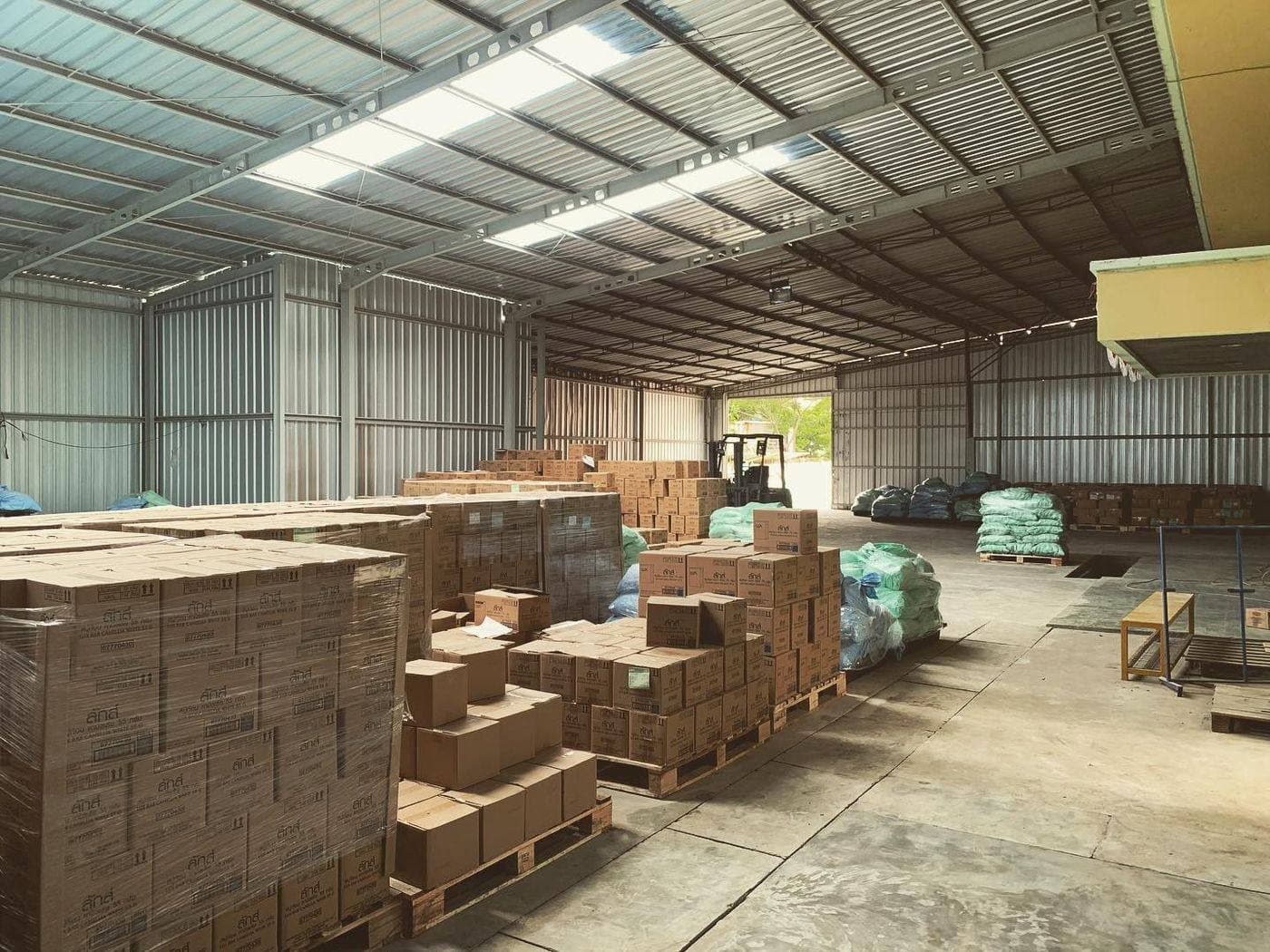 Site photo of a warehouse interior with storage pallets and steel roof trusses